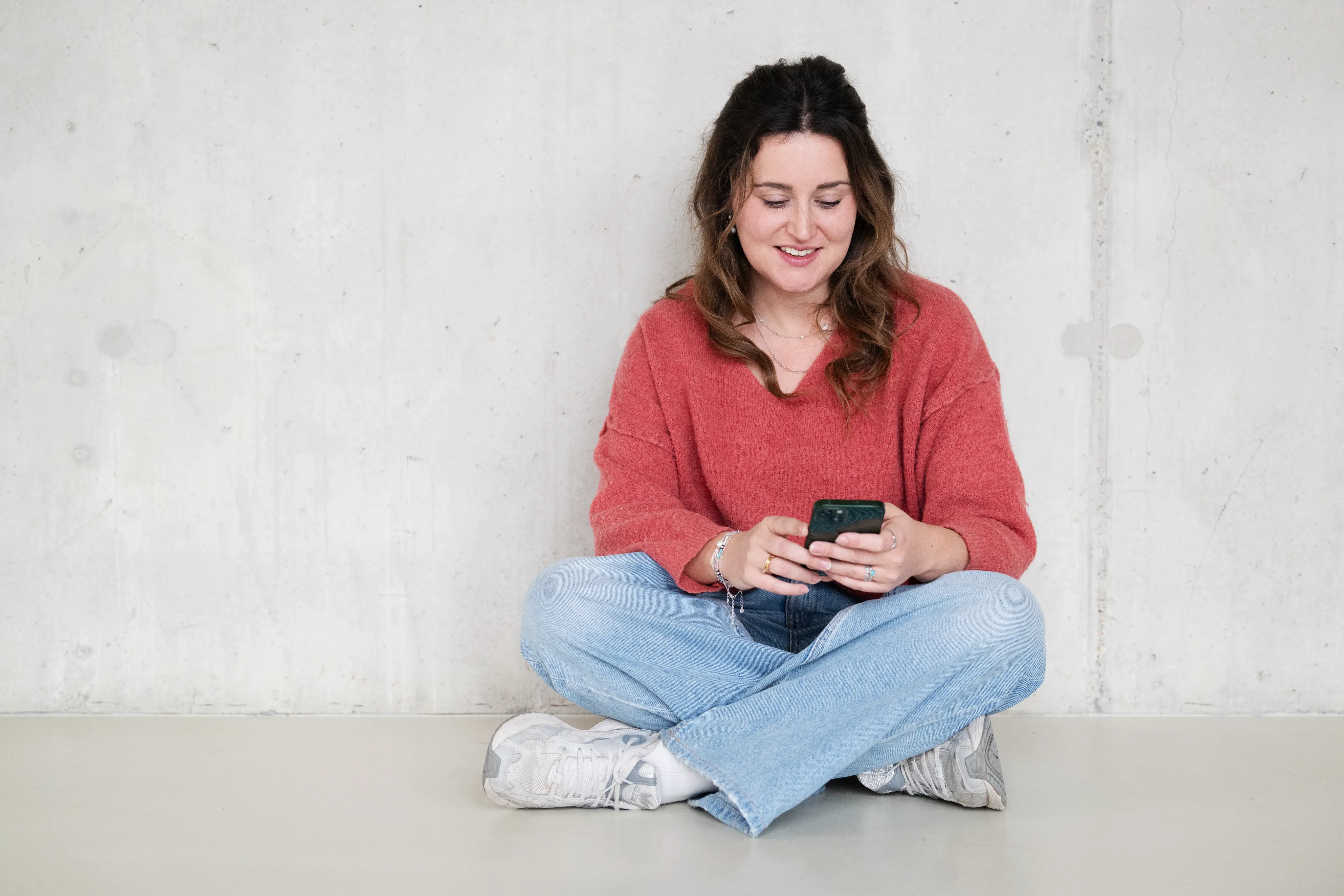 Vrouw zit op de grond en kijkt naar telefoon