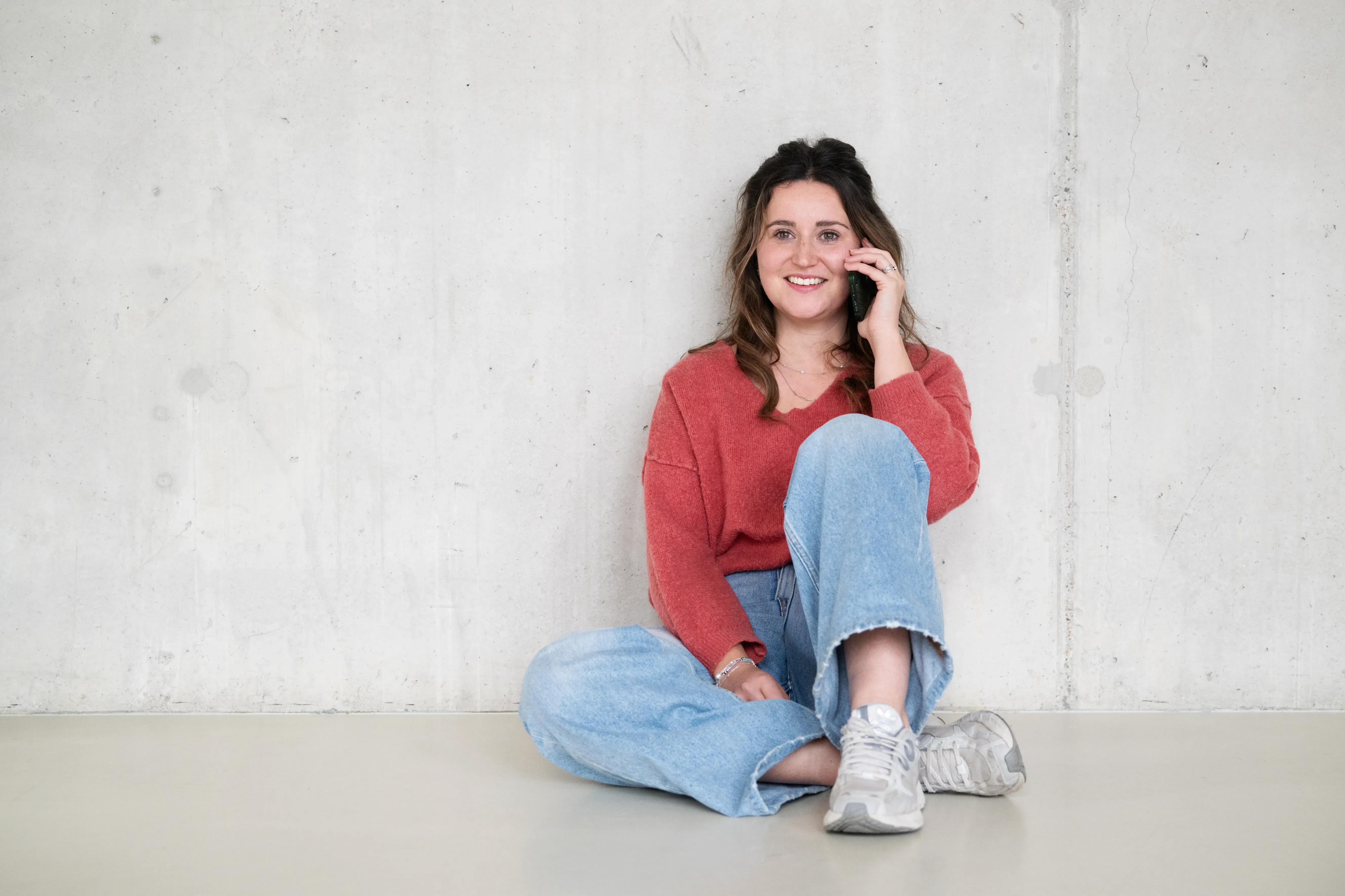 Vrouw zit op de grond en is aan het bellen
