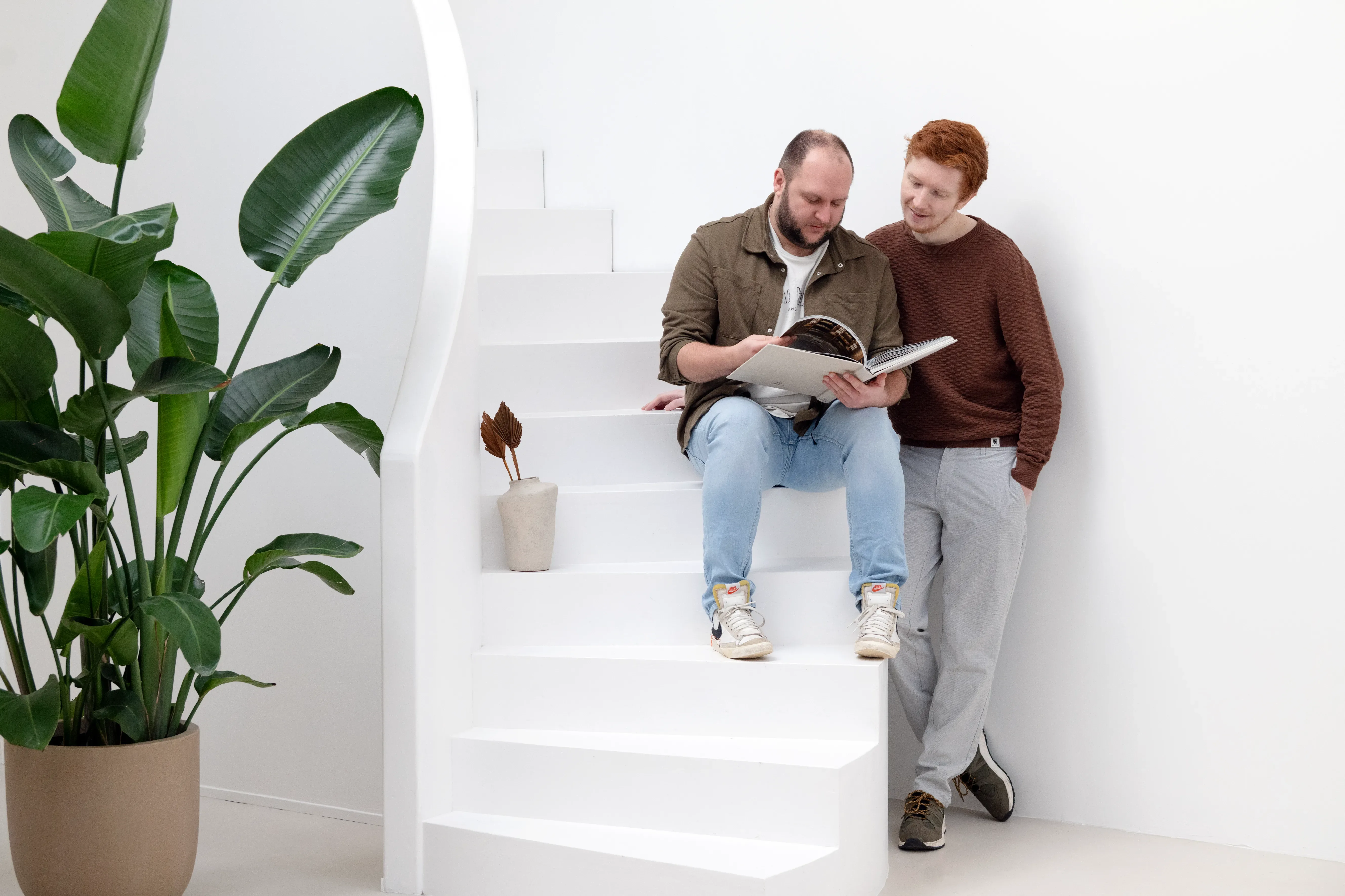 Twee mannen zitten op trap een boek te lezen