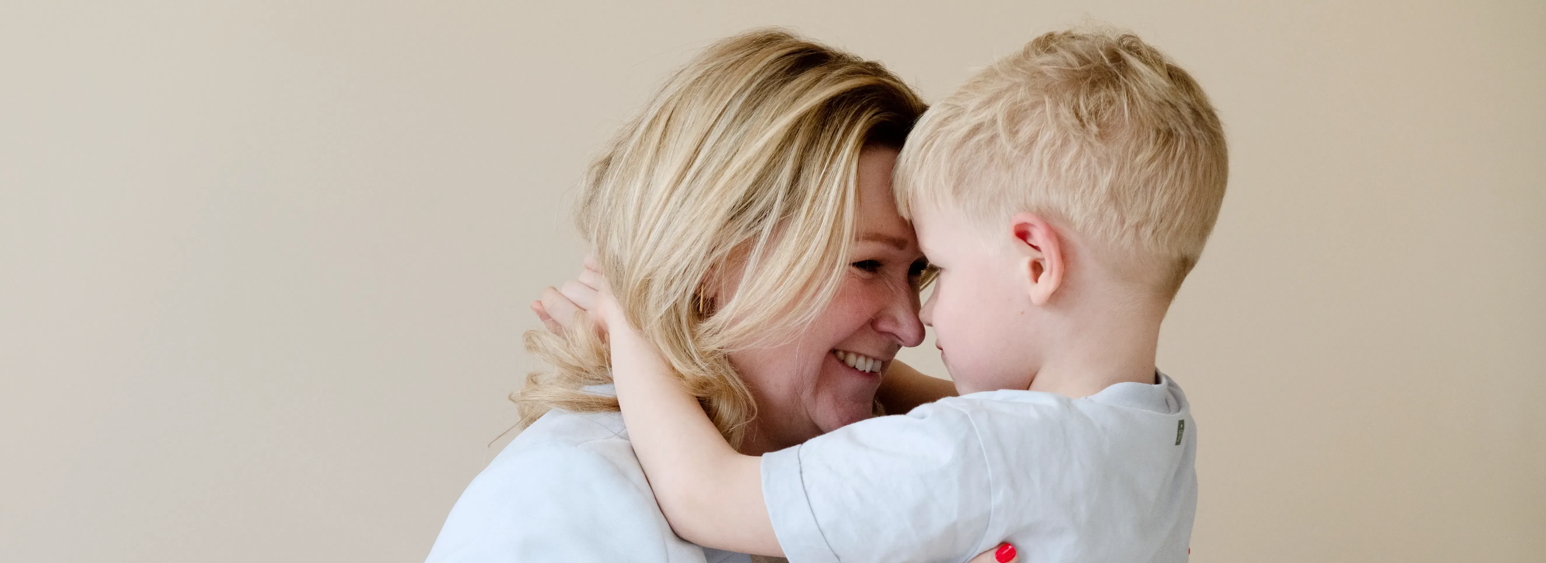 vrouw en zoontje knuffelend met hoofd tegen hoofd