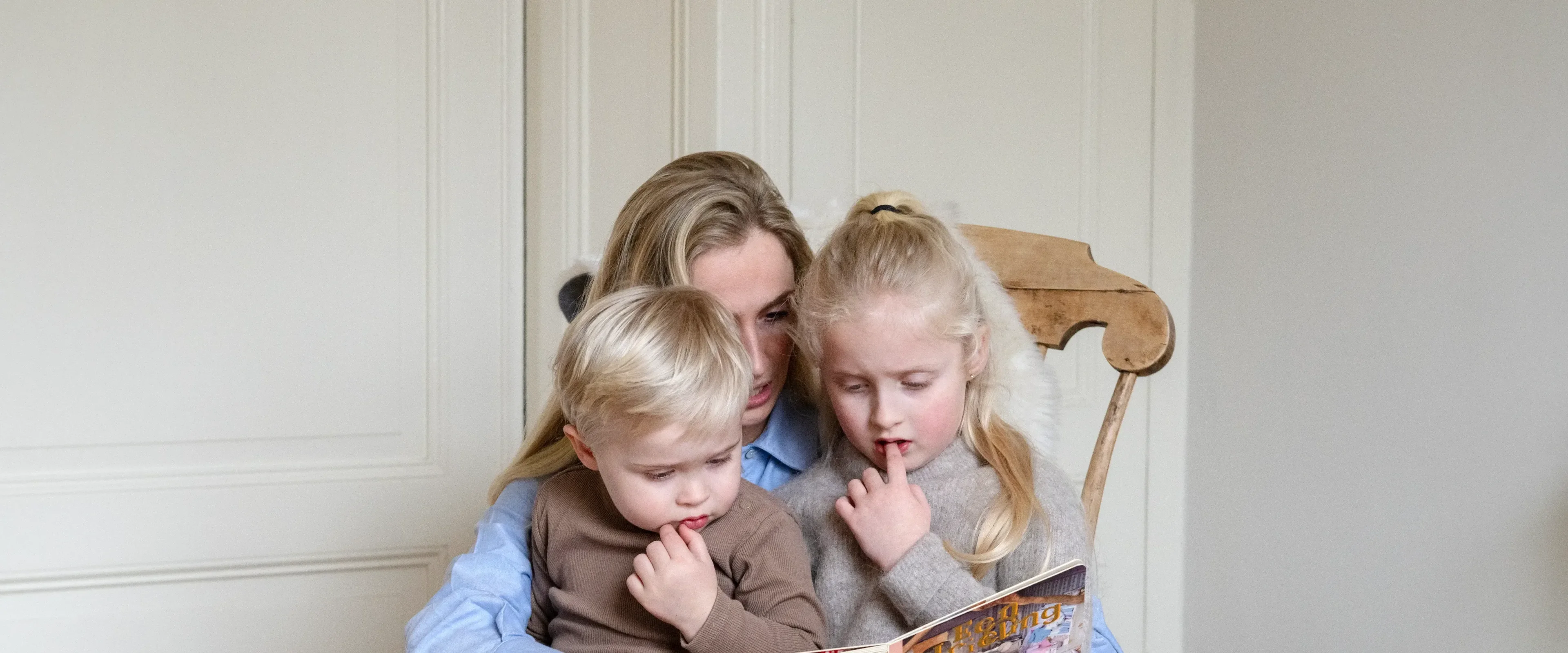 Moeder met dochter en zoon boekje aan het lezen in wipstoel
