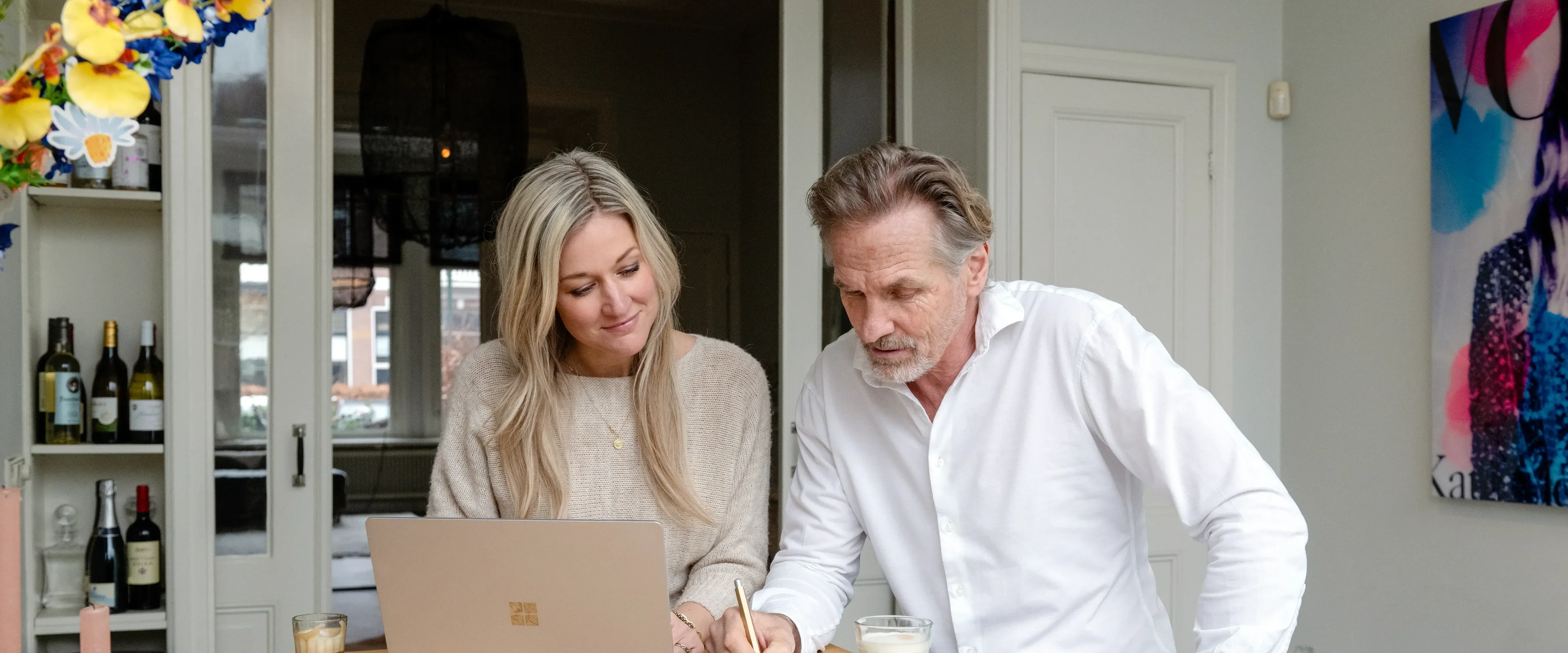 Man en vrouw zitten aan tafel en kijken naar laptop