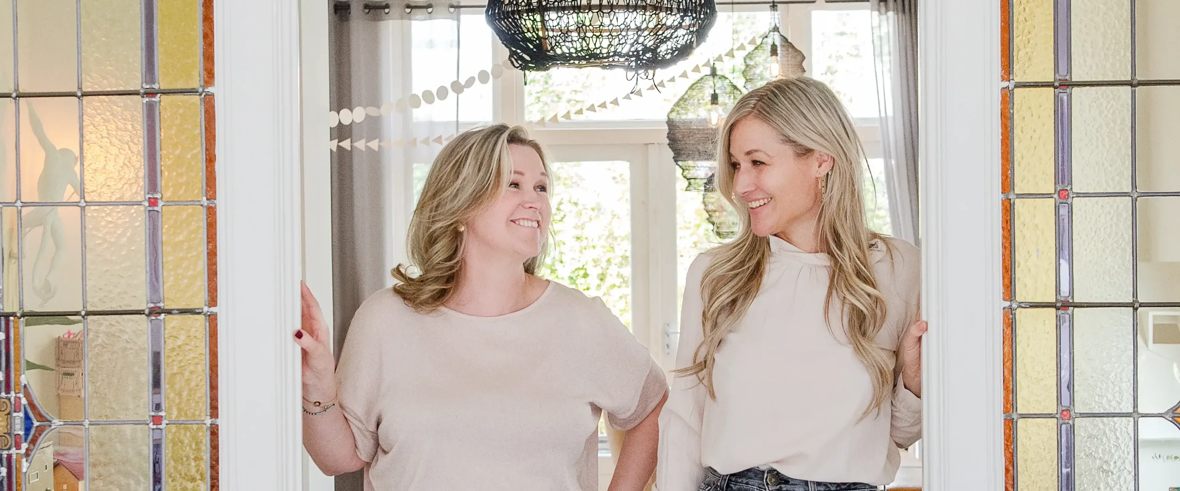 Twee vrouwen staan in schuifdeuren en lachen naar elkaar