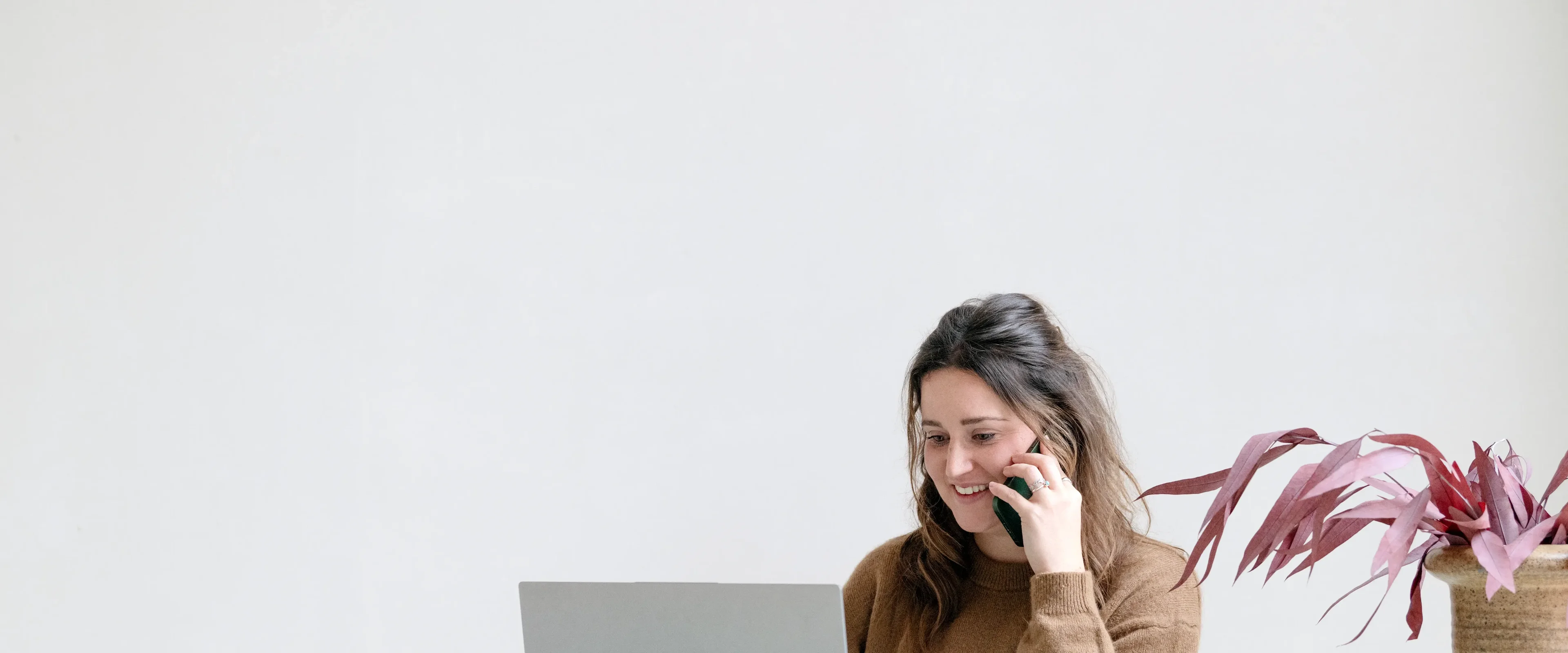 Vrouw aan het bellen en kijkt naar laptop