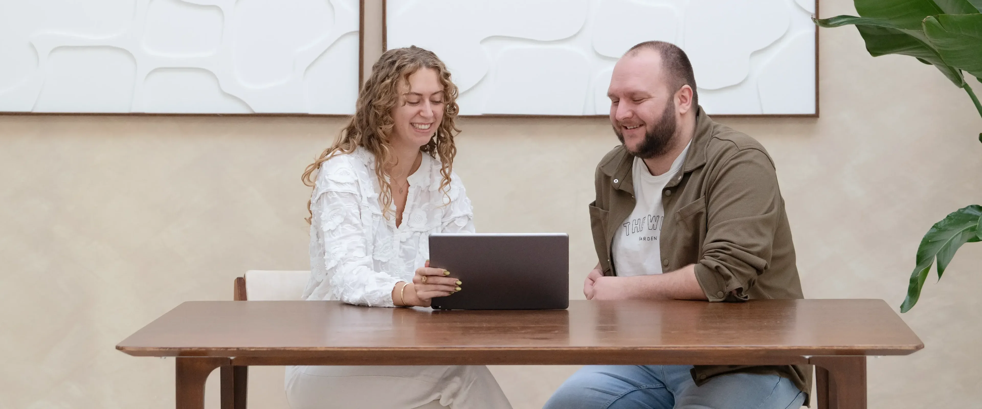 Man en vrouw aan tafel kijkend naar laptop