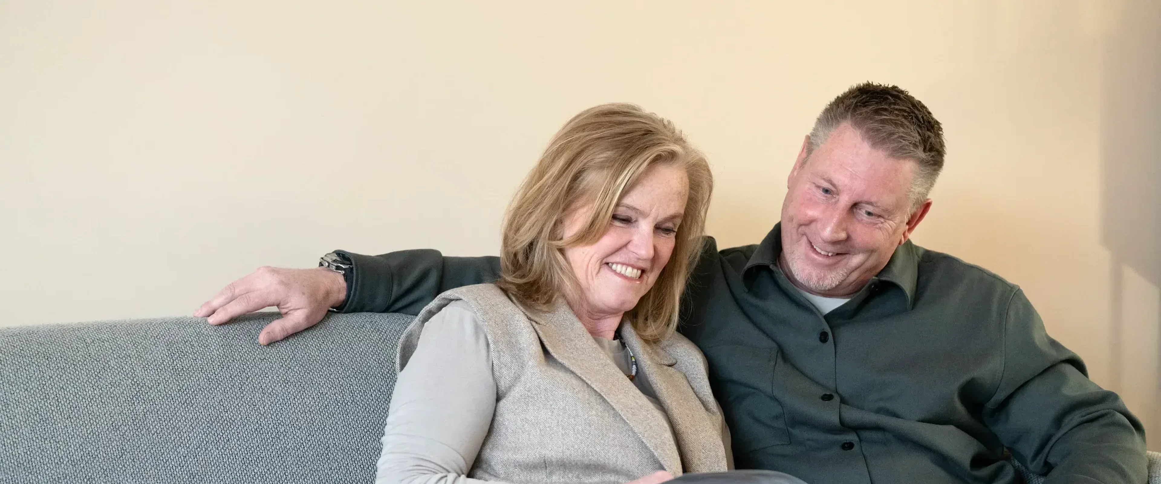 Man en vrouw zitten op bank en lezen boekje
