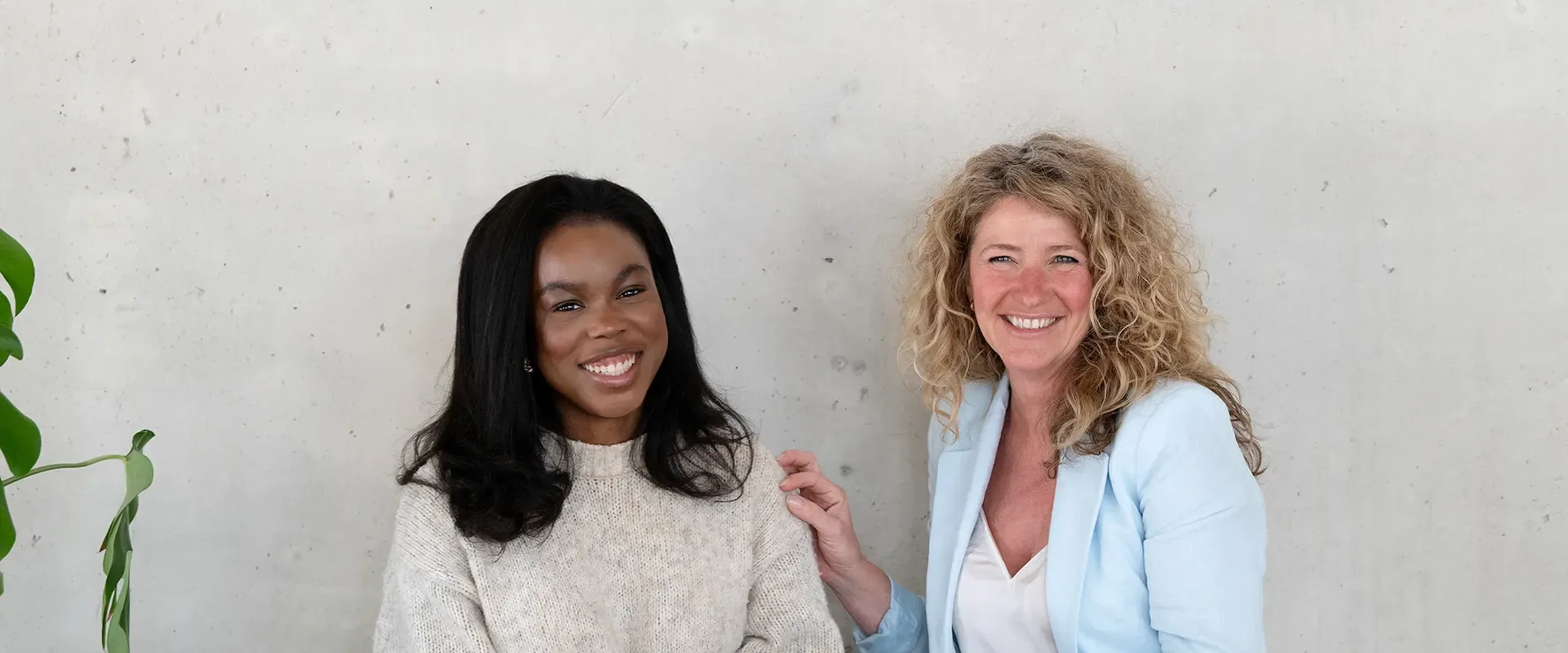 2 vrouwen aan tafel lachend naar de camera