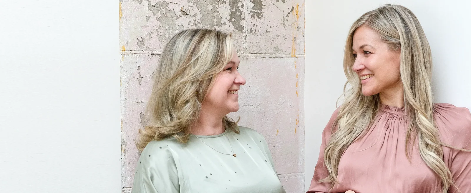 Twee vrouwen naast elkaar, naar elkaar aan het glimlachen