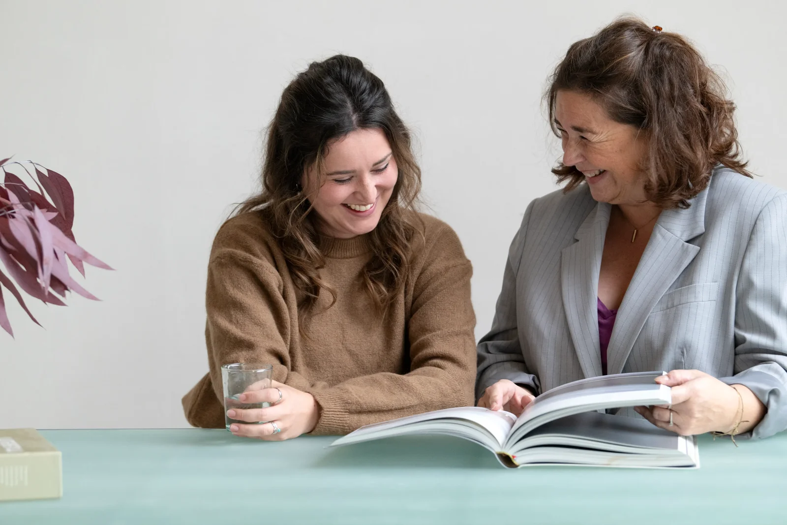 Twee vrouwen aan tafel bladerend door boek