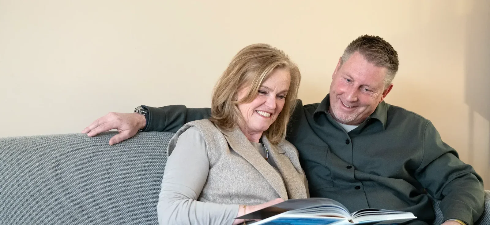 Man en vrouw zitten op bank en lezen boekje